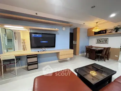Spacious living room with modern decor and dining area, featuring a wall-mounted TV and elegant lighting.