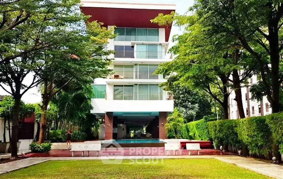 Modern apartment building with lush greenery and spacious outdoor area.