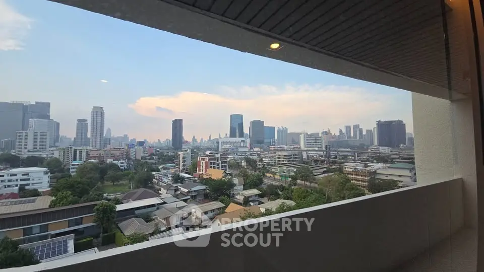 Stunning cityscape view from a high-rise balcony, showcasing urban skyline and lush greenery.