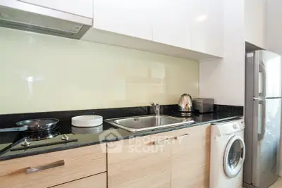 Modern kitchen with sleek appliances and washing machine in compact layout.