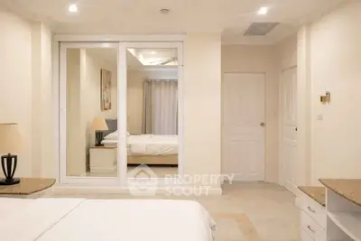 Spacious bedroom with mirrored closet doors and elegant lighting