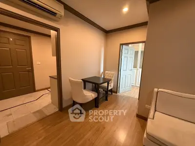 Cozy apartment interior with wooden flooring and modern furniture, featuring a small dining area and comfortable seating.