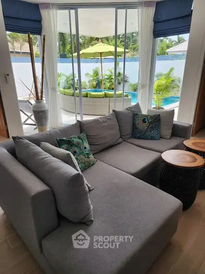 Luxurious living room with pool view and stylish decor in tropical setting.