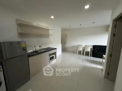 Modern apartment with sleek kitchen and spacious living area, featuring minimalist design and bright lighting.