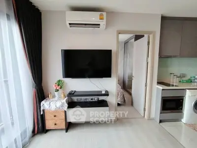 Modern apartment interior with sleek kitchen and cozy living area featuring wall-mounted TV and air conditioning.