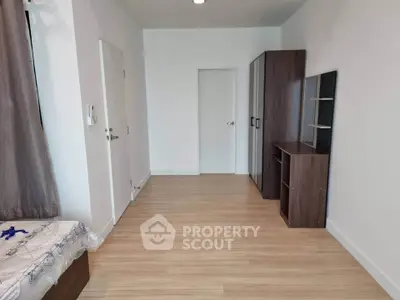 Spacious bedroom with wooden flooring and modern furniture in a minimalist design.