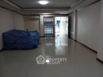 Spacious empty room with glossy tiled floors and large windows for natural light.