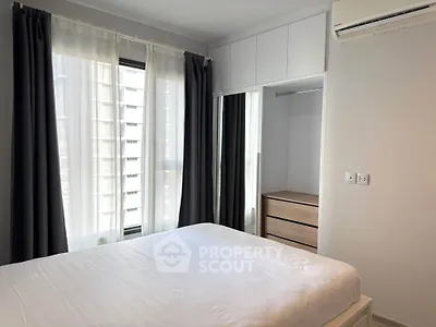 Modern bedroom with large window and built-in wardrobe in a stylish apartment.