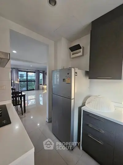 Modern kitchen with sleek appliances and open layout leading to dining area.