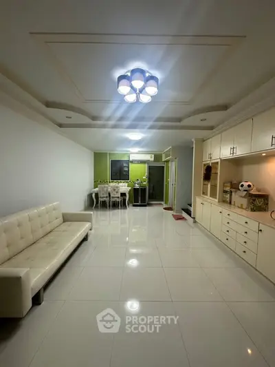 Spacious modern living room with sleek tile flooring and elegant ceiling lights.