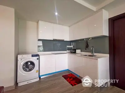 Modern kitchen with sleek cabinets and washing machine in a compact layout