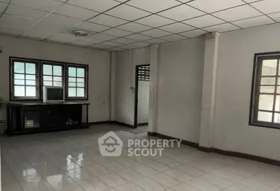 Spacious empty living room with tiled floor and large windows for natural light.