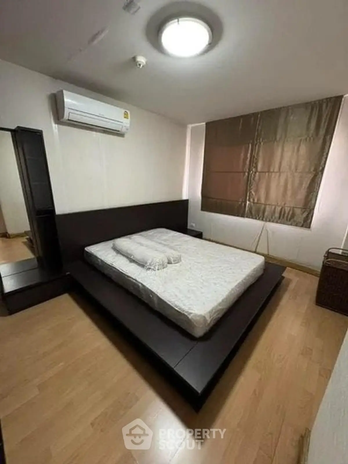 Spacious bedroom with modern platform bed and air conditioning in a stylish apartment.