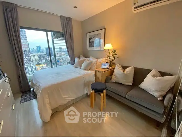 Cozy bedroom with city view, featuring a comfortable bed and stylish sofa, perfect for urban living.