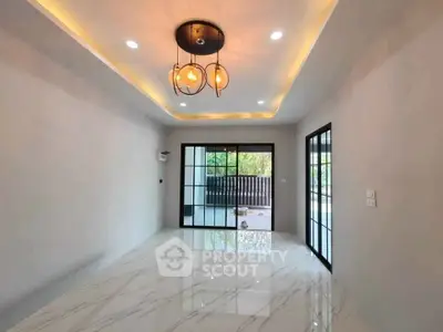 Spacious modern living room with elegant lighting and large glass doors opening to a serene balcony view.