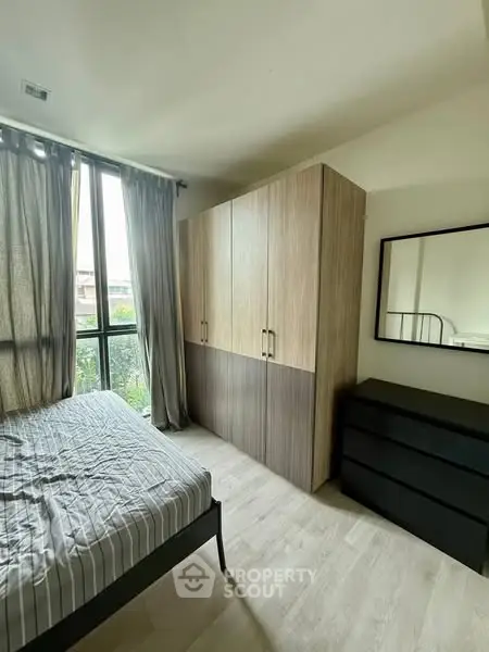 Cozy bedroom with large window and modern wardrobe in a stylish apartment