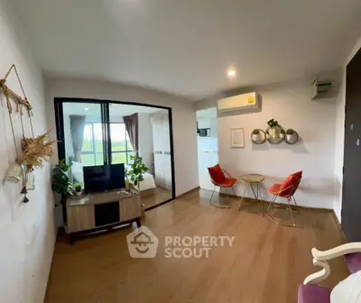 Modern living room with stylish decor and glass partition, featuring wooden flooring and cozy seating area.