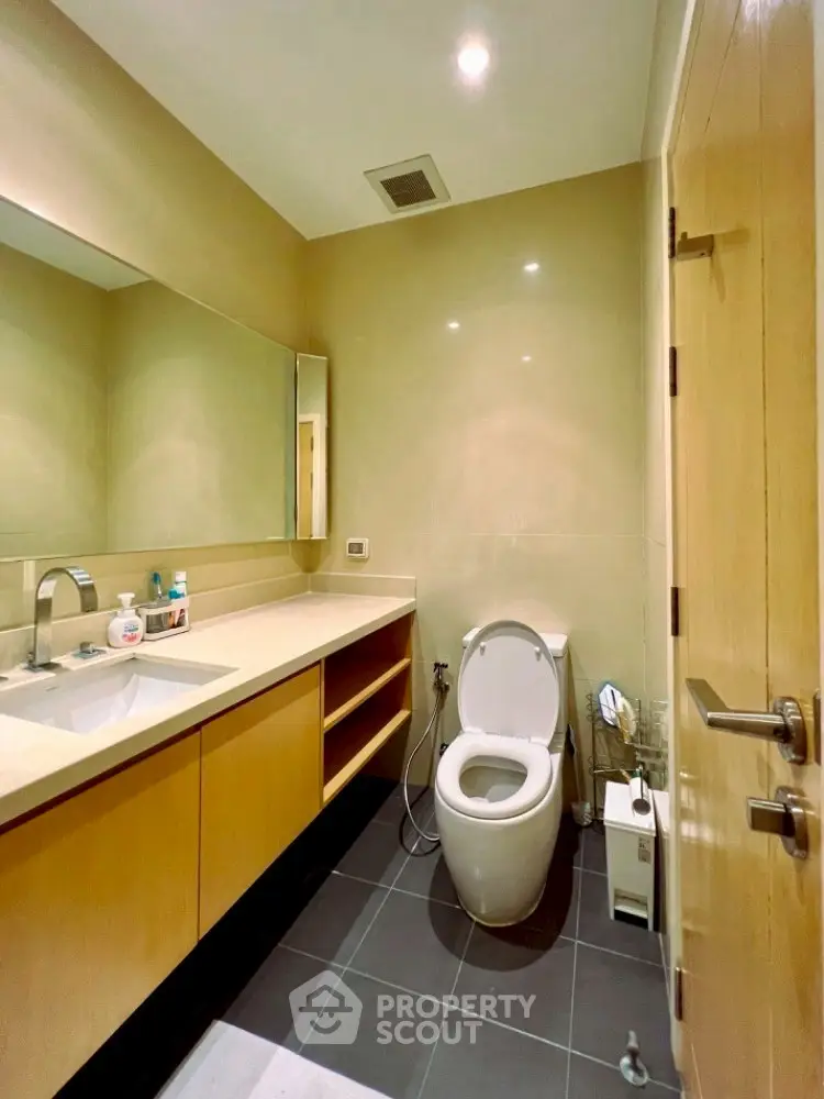 Modern bathroom with sleek fixtures and ample lighting, featuring a large mirror and contemporary design.