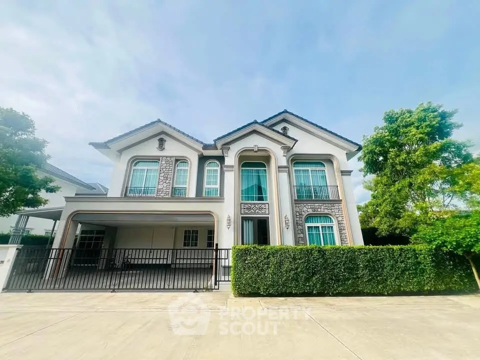 Elegant two-story house with manicured hedges and spacious driveway in a serene neighborhood.