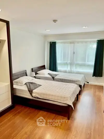 Spacious bedroom with twin beds and large window for natural light.