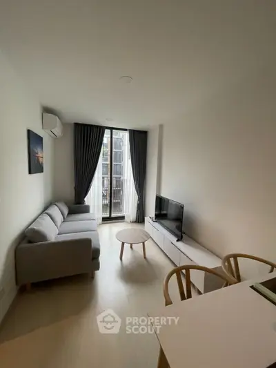 Modern living room with sleek furniture and large window offering natural light.