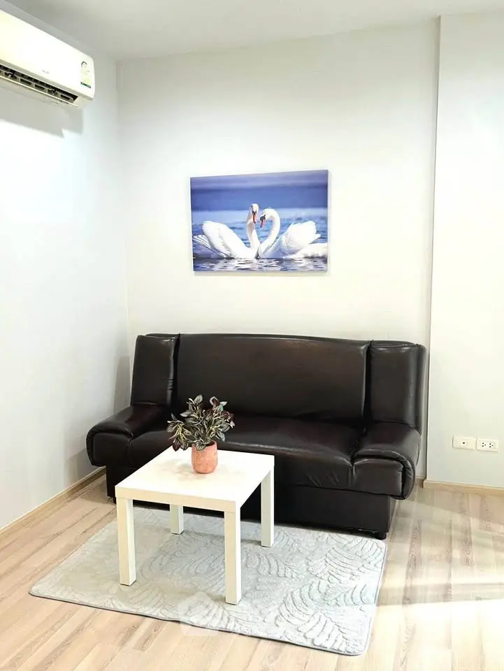 Cozy living room with leather sofa and elegant swan artwork, perfect for relaxation.