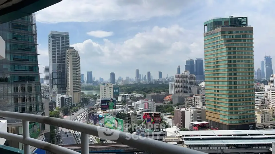 Stunning cityscape view from a high-rise balcony overlooking urban skyline and lush park.