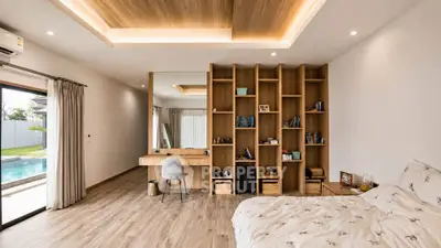 Luxurious bedroom with pool view, wooden flooring, and elegant built-in shelving.