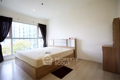 Spacious bedroom with large window and modern wooden furniture