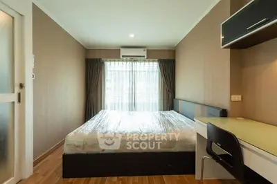 Modern bedroom with natural light, featuring a comfortable bed and sleek workspace.
