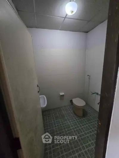 Basic bathroom with tiled floor and simple fixtures, ideal for renovation.