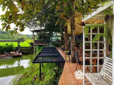 Charming outdoor terrace with lush greenery and serene water view, perfect for relaxation and nature lovers.