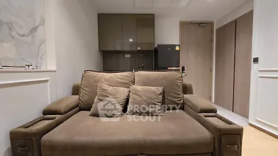 Cozy living room with plush brown sofa and compact kitchenette in modern apartment.