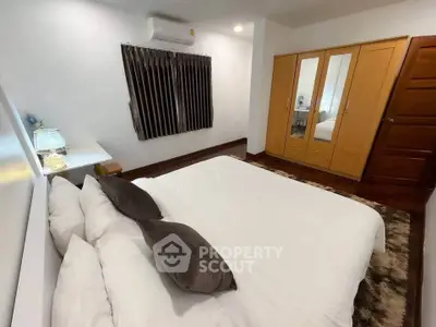 Cozy bedroom with wooden wardrobe and plush bedding in modern apartment.
