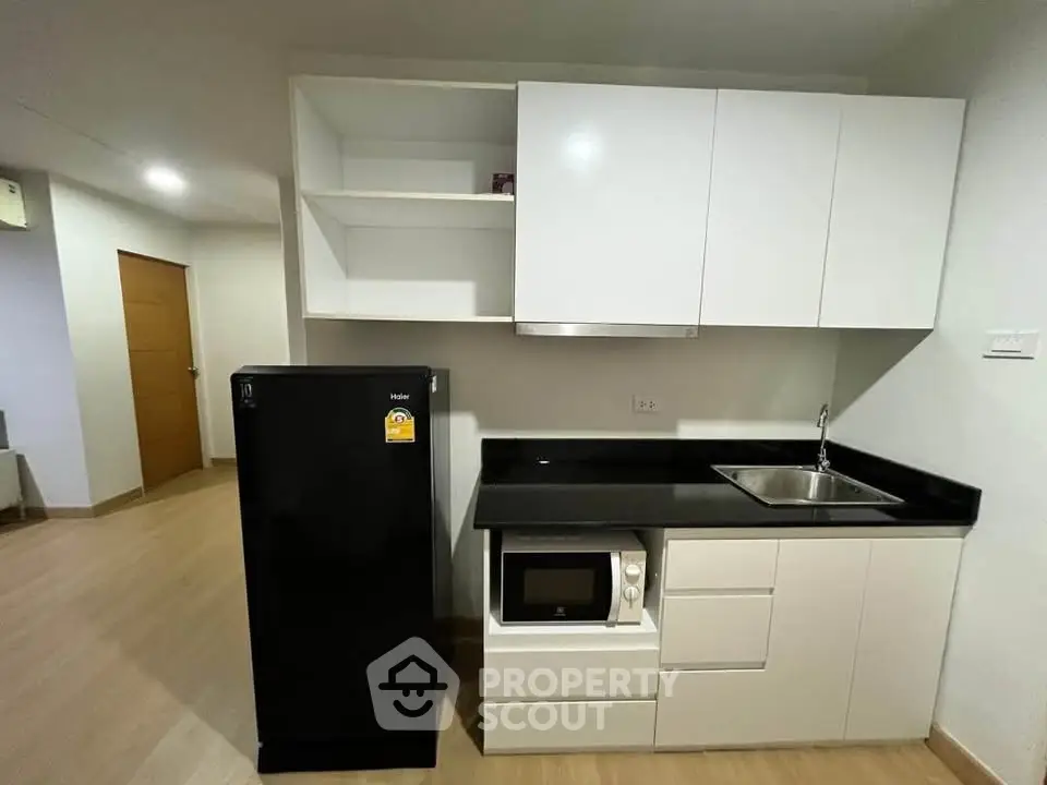 Modern kitchen with sleek black appliances and white cabinetry in a compact layout.