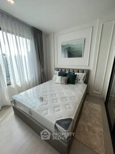 Modern bedroom with stylish decor and large window offering natural light.