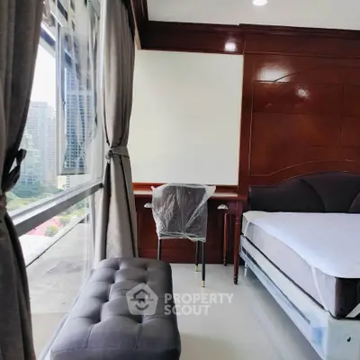 Modern bedroom with city view, elegant wood paneling, and cozy seating area.