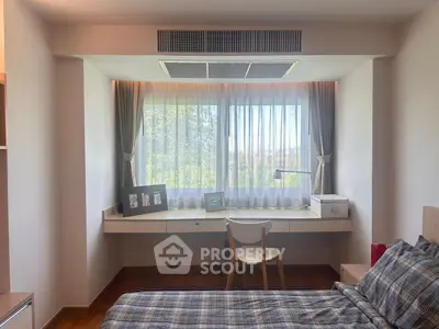 Cozy bedroom with large window and desk, perfect for relaxation and work.