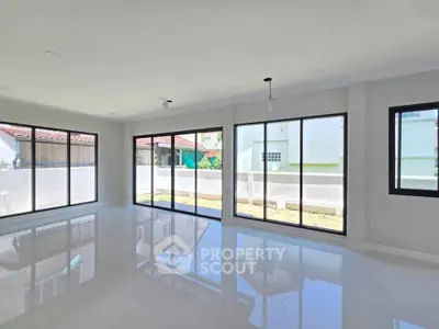 Spacious modern living room with large windows and glossy floors in a bright home.