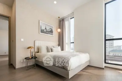 Luxurious modern bedroom with elegant decor and large windows offering city views.