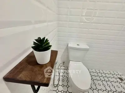 Modern bathroom with stylish white tiles and a potted plant for a fresh look.