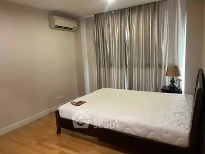 Cozy bedroom with air conditioning and elegant curtains, featuring a comfortable bed and stylish lamp.