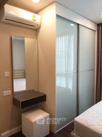 Modern bedroom with sleek sliding closet doors and wall-mounted air conditioning unit.