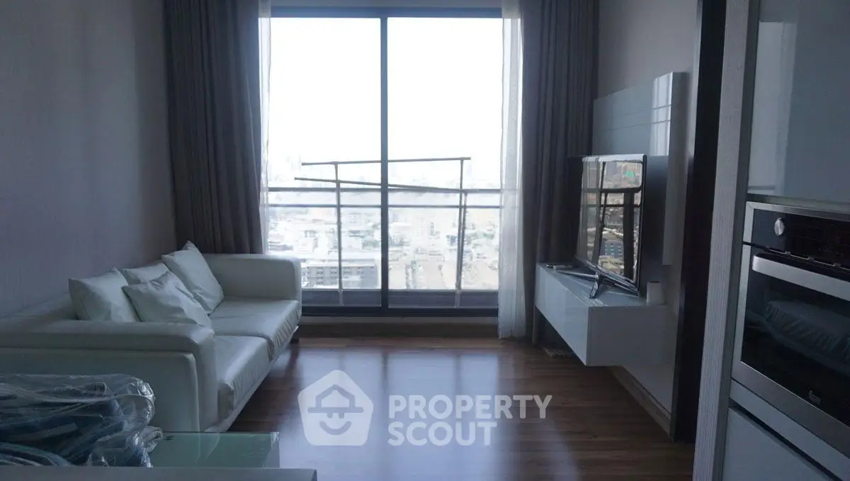 Modern living room with city view, sleek furniture, and wooden flooring in a high-rise apartment.