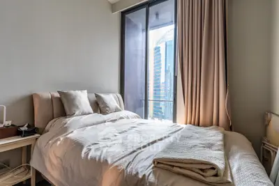 Modern bedroom with city view and cozy bedding in high-rise apartment