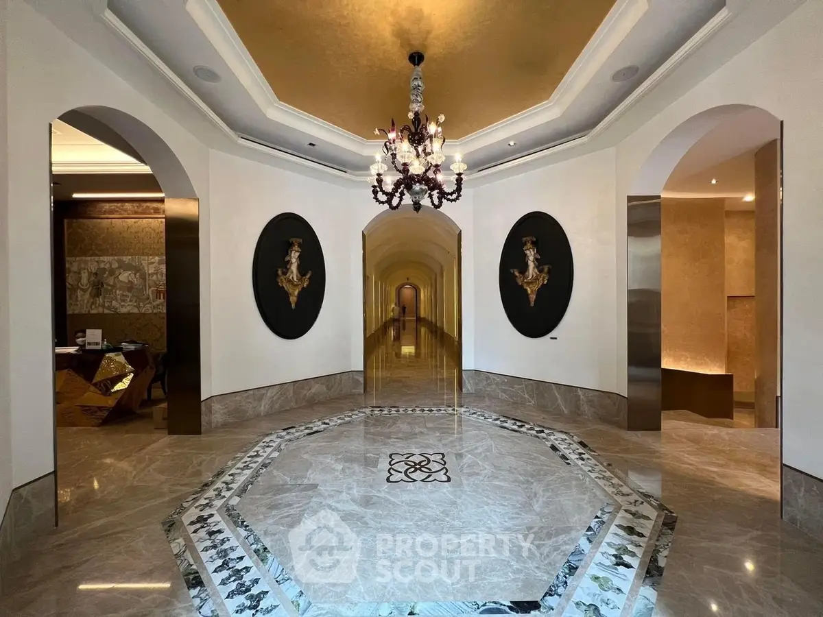 Luxurious building entrance with elegant chandelier and marble flooring, showcasing opulent design.