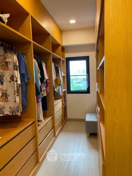 Spacious walk-in closet with wooden shelves and natural light