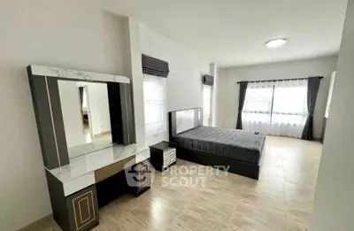 Spacious modern bedroom with elegant vanity and large windows for natural light.