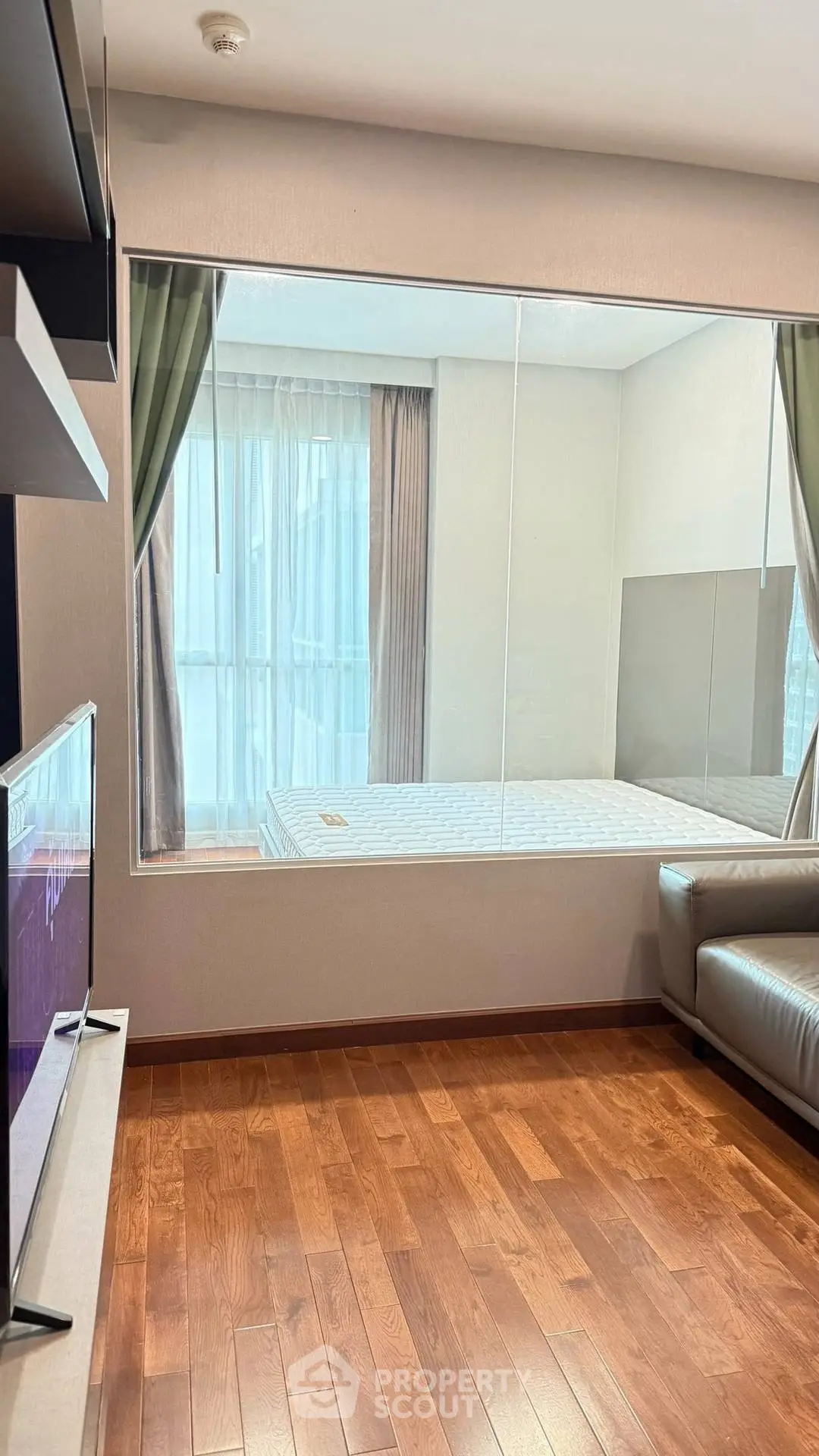 Modern apartment with hardwood floors and large window in cozy living area.