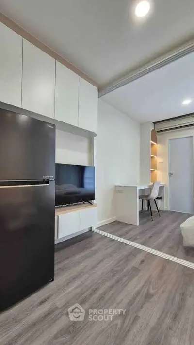Modern apartment interior with sleek kitchen and cozy living area, featuring stylish wood flooring and built-in storage.